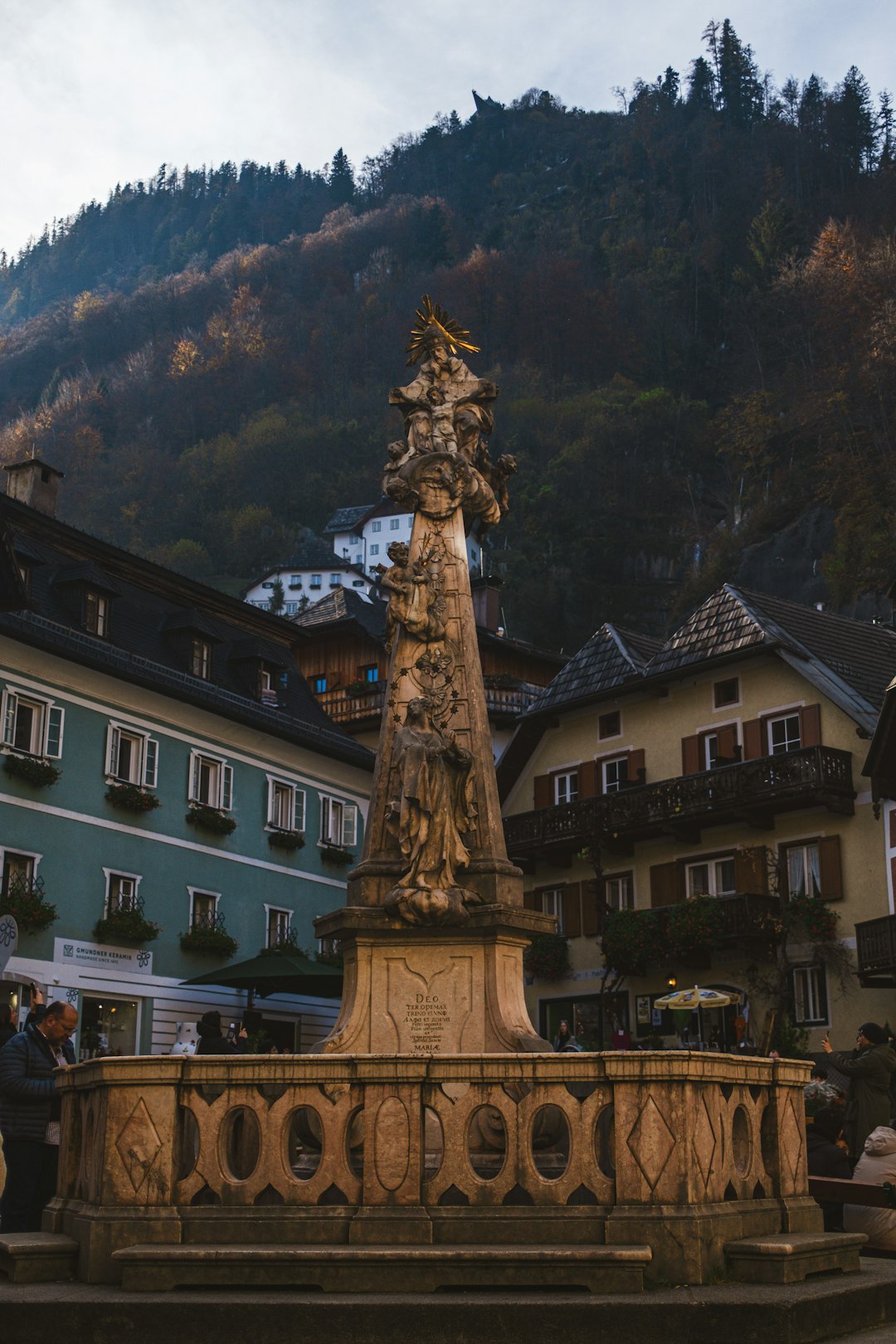 Une place de village suisse pittoresque pavée de pierres naturelles. Des bâtiments historiques avec des jardinières fleuries bordent la place. Le soleil de fin d