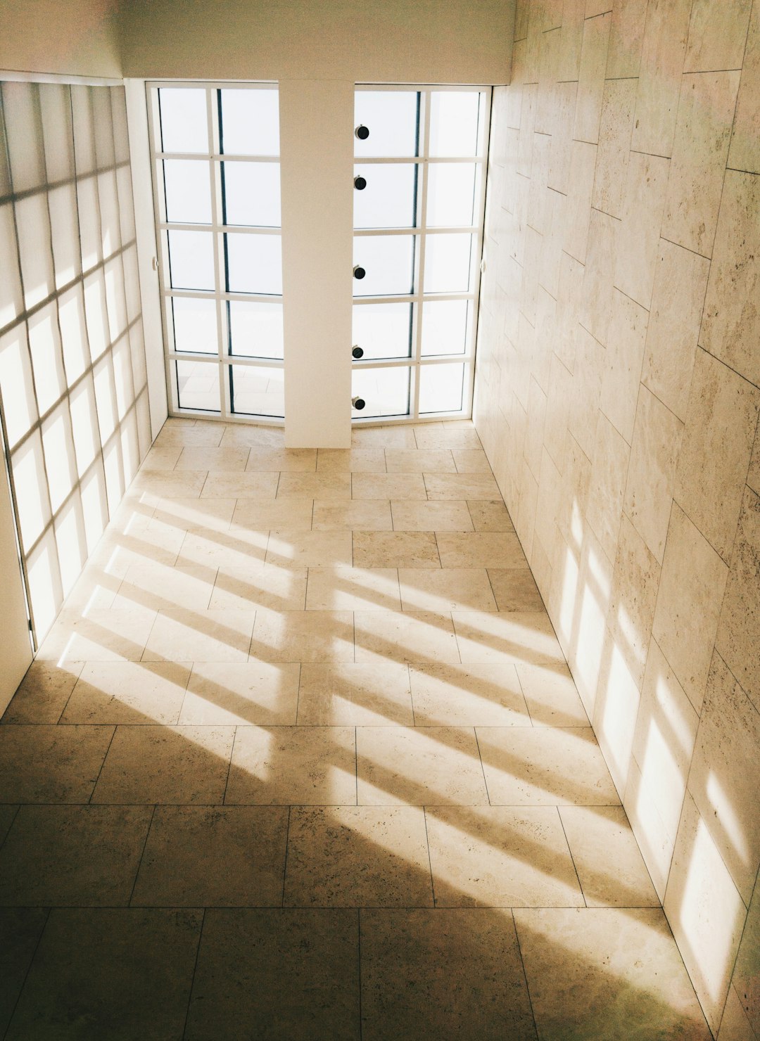 Un architecte en chemise blanche examine attentivement un grand échantillon de dalle en marbre gris dans un showroom lumineux et moderne. Photographe: R Architecture sur Unsplash