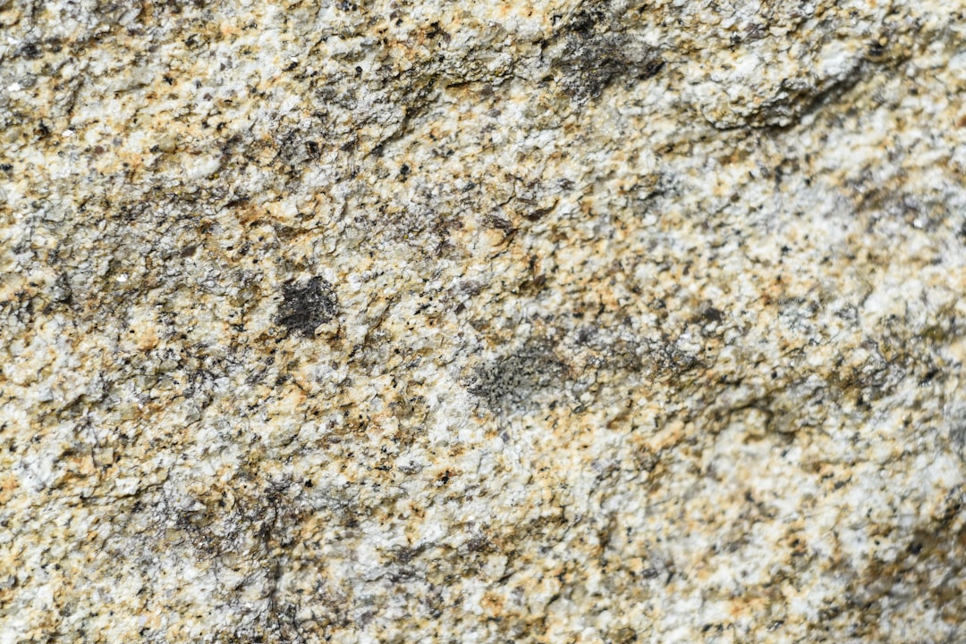 Gros plan sur une surface de granit gris texturé, mettant en évidence les motifs minéraux. Photographie par Michael Dziedzic sur Unsplash.