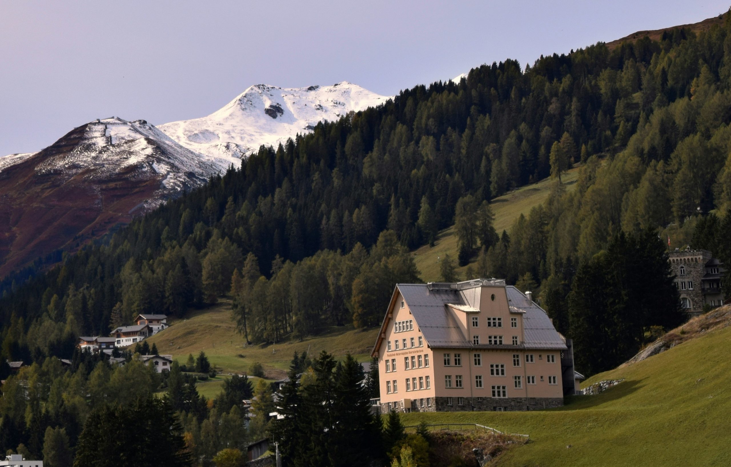 Outdoor luxury hotel terrace in the Swiss Alps designed with natural stone pavers, snowy mountains in background
