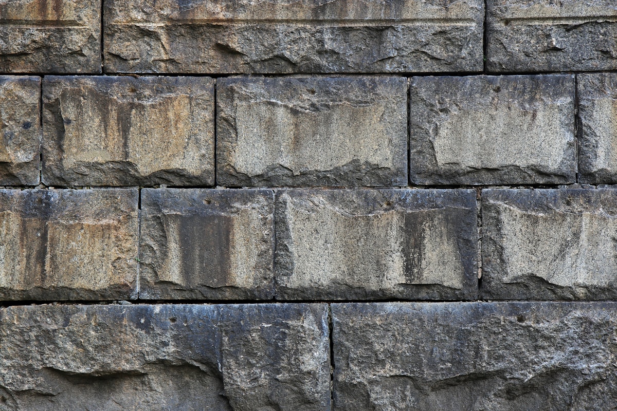Weathered stone wall with dark streaks.