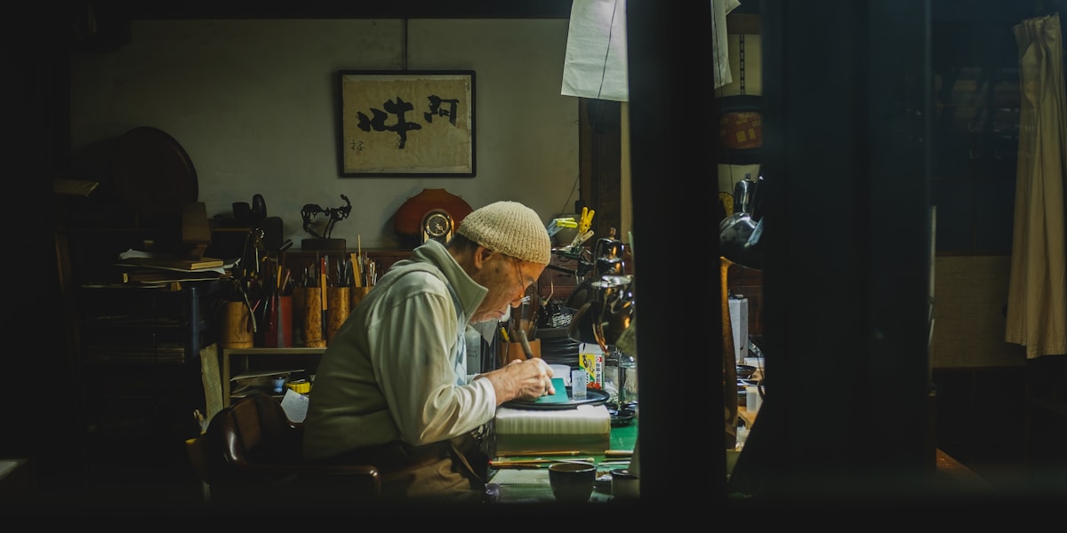 Elderly craftsman working diligently at a desk.