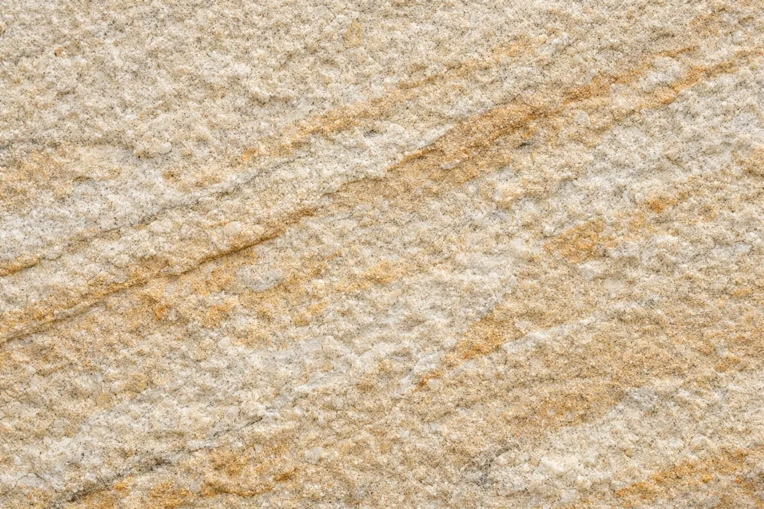 Close-up macro view of torros flamed sandstone surface showing textured grain patterns, natural mineral veins, and rough flamed finish with warm beige and ochre tones under natural daylight, product photography style