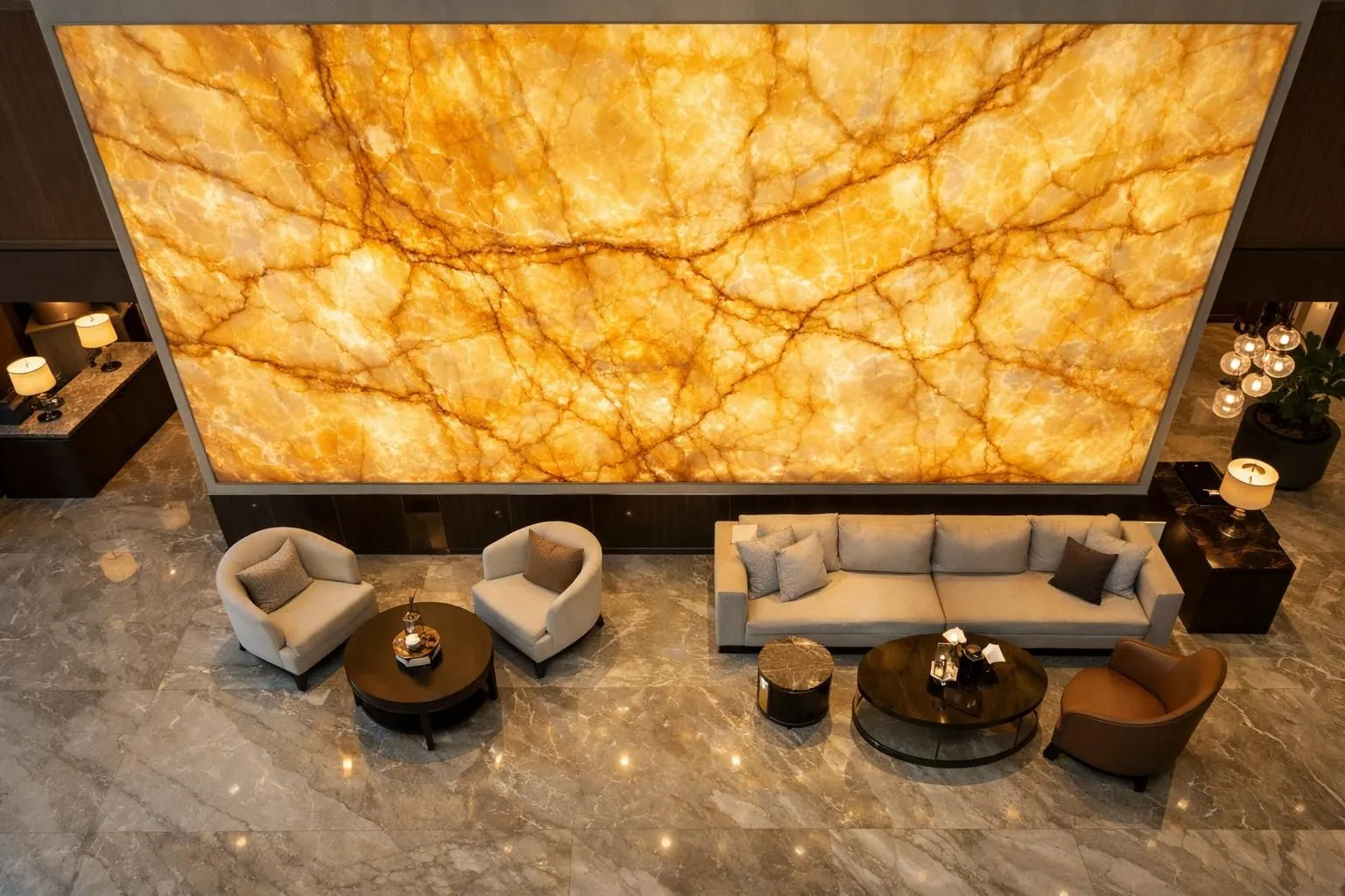 Luxury hotel lobby featuring a dramatic backlit translucent honey-colored onyx wall panel stretching from floor to ceiling, warm golden glow illuminating the natural veining patterns, modern elegant interior with polished marble floors and designer furniture, ambient soft lighting creating sophisticated atmosphere