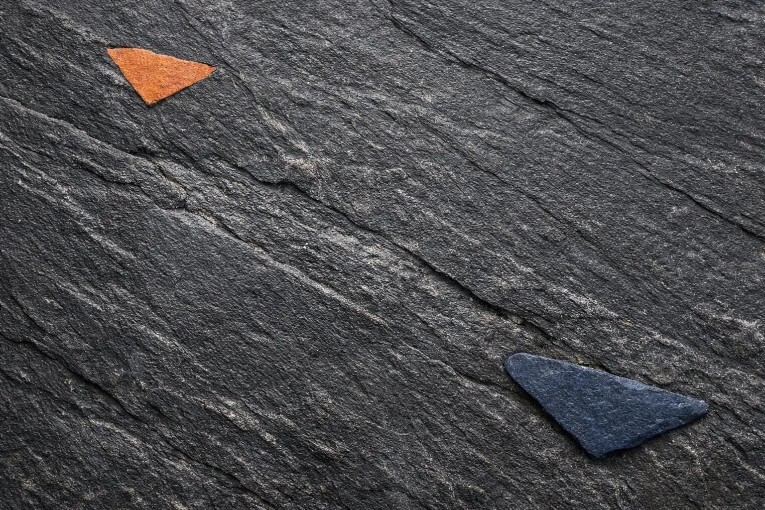 Close-up photograph of dark Black Diamond phyllite stone with aged textured surface showing natural layered mineral patterns, anthracite gray to deep black coloring, outdoor weathered finish with subtle striations and anti-slip texture visible on stone slab