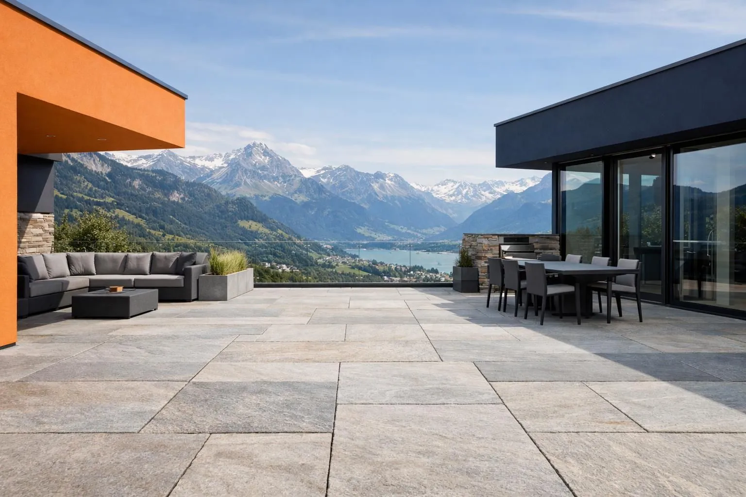 Elegant outdoor terrace with large natural stone slabs in granite or sandstone, showing high-quality installation with wide joints, set against a Swiss mountain landscape, professional construction materials displayed, realistic photography style with focus on durable stone textures and luxury residential architecture