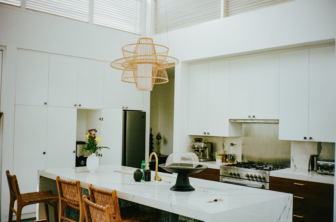Cuisine moderne et lumineuse avec un grand îlot central en marbre blanc aux veines grises, entouré de tabourets de bar design.