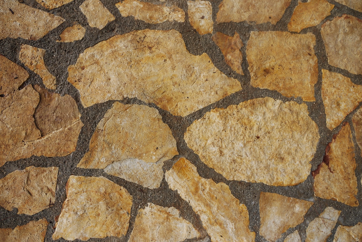 Motif de pierres naturelles irrégulières dans des tons ocres et gris.