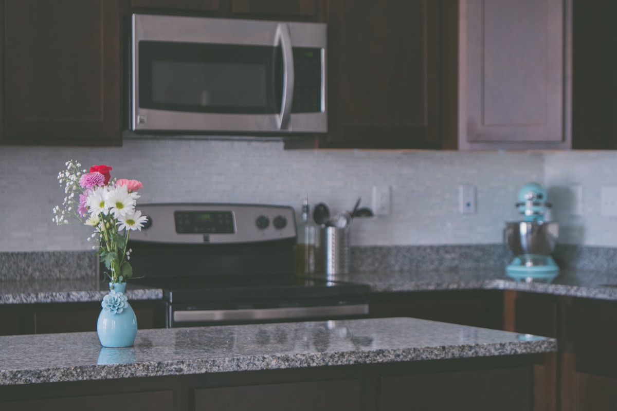 Cuisine moderne avec fleurs, électroménagers et comptoir en granit.