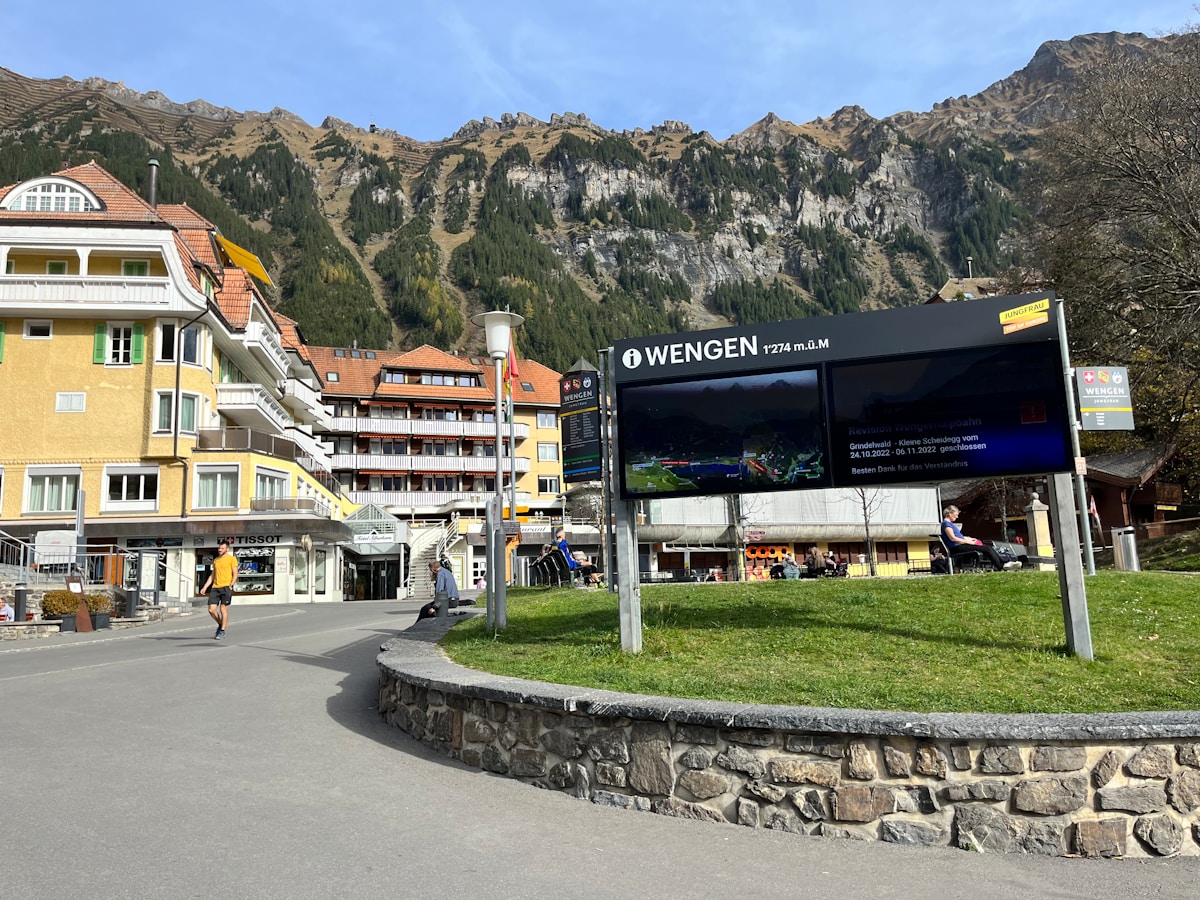 Paysage montagneux avec village alpin, panneaux d'information et activités de plein air.
