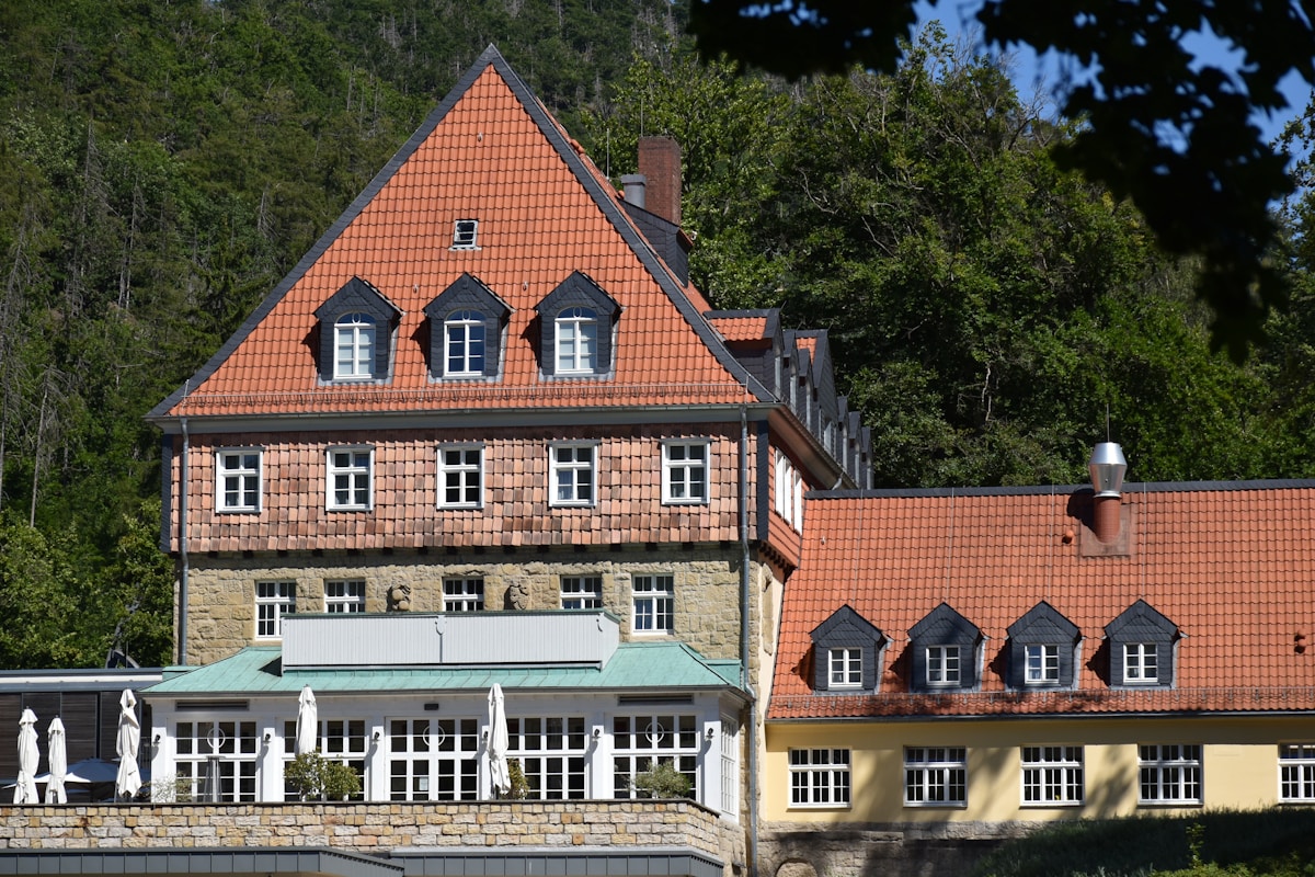 Bâtiment historique à toits de tuiles rouges dans un cadre forestier.