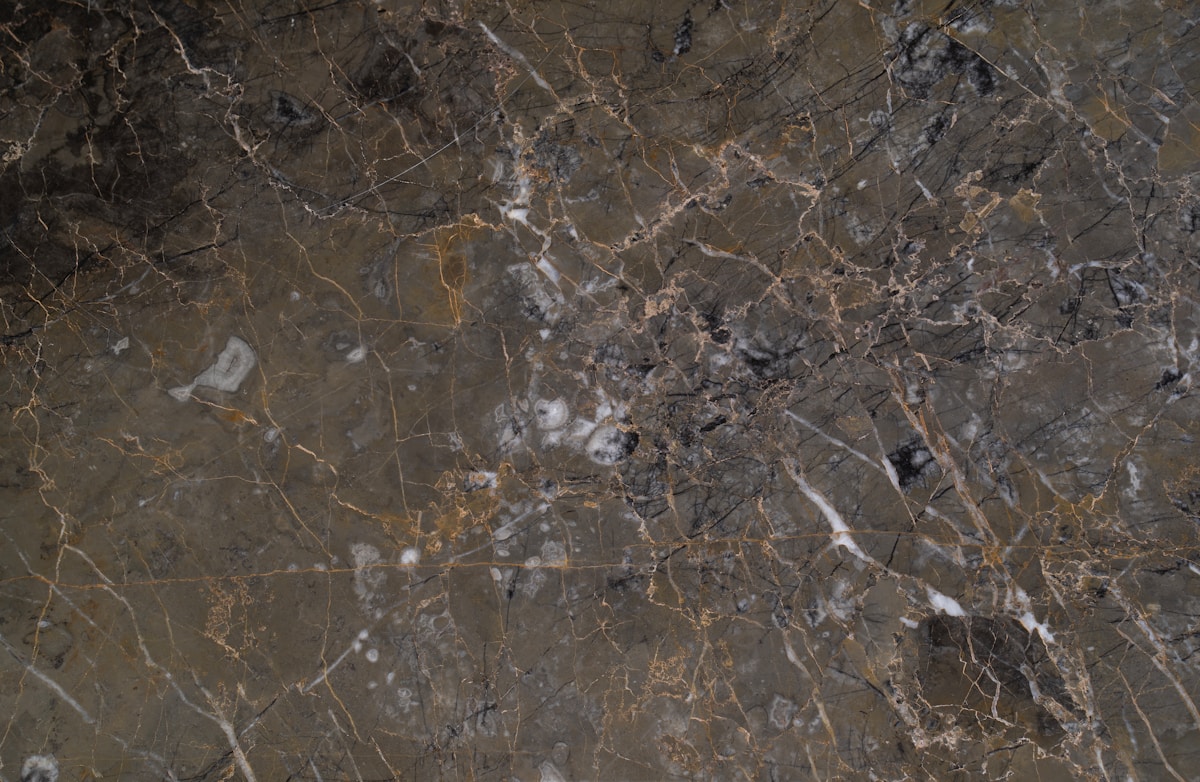 Texture de marbre brun foncé avec des veines dorées et grises.