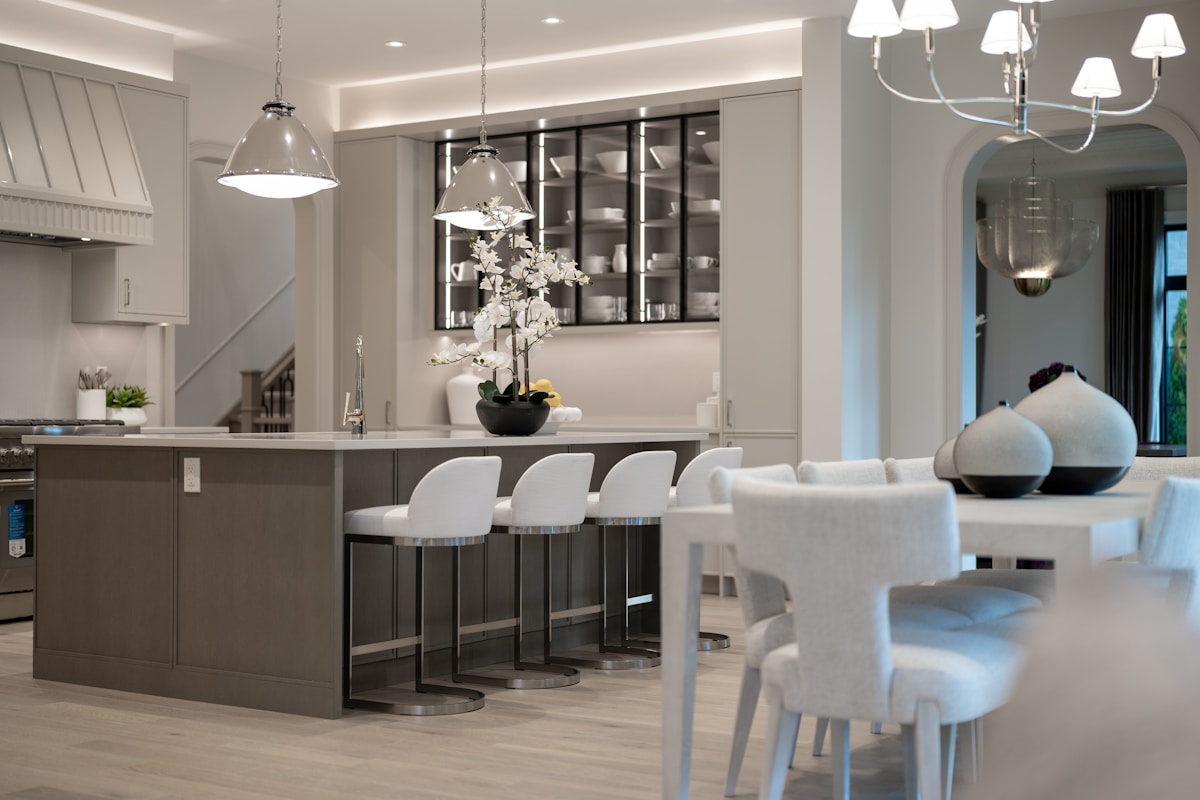 Cuisine moderne et élégante avec îlot central, luminaires suspendus et décoration florale.