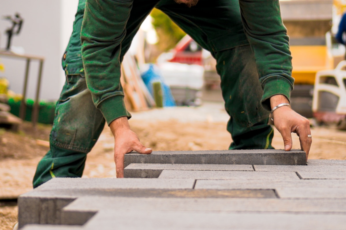 Ouvrier en uniforme vert posant des briques de construction.
