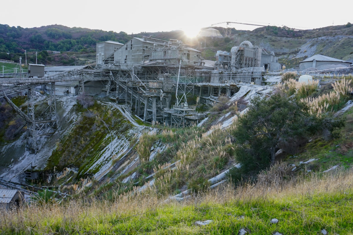 Paysage industriel abandonné avec structures métalliques et végétation.