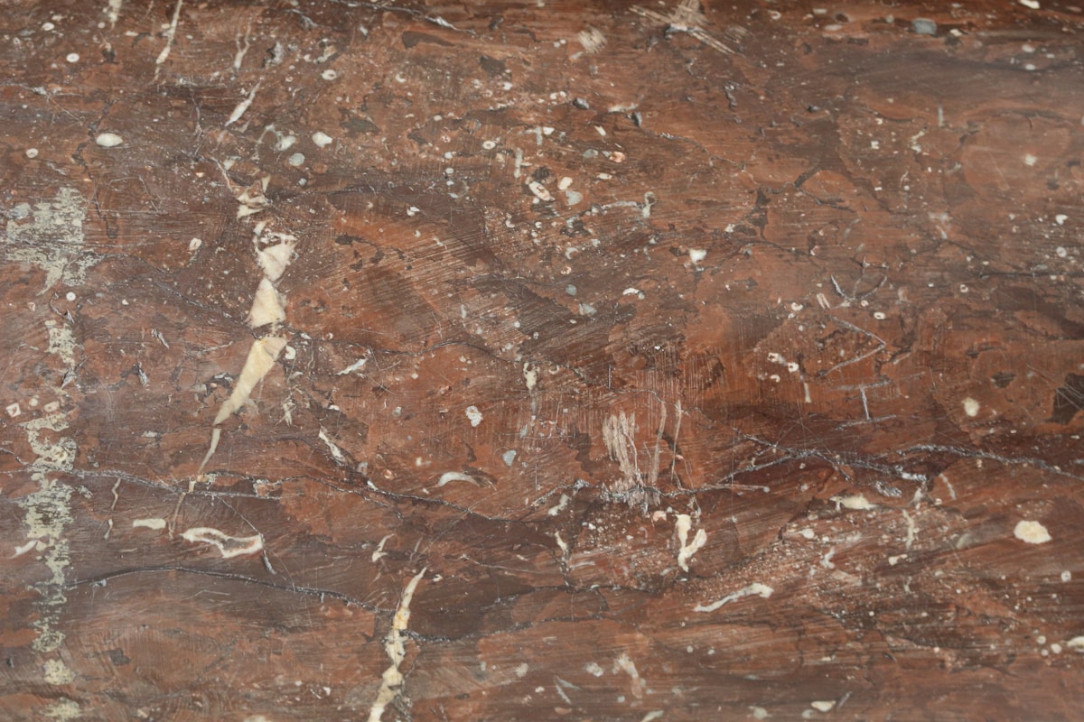 Texture de marbre brun foncé avec des veines et des taches blanches.