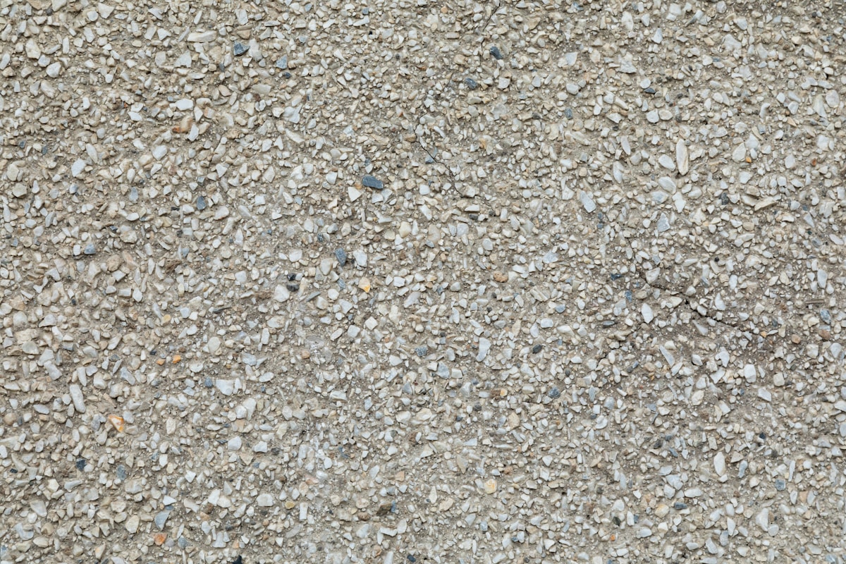 Texture de gravier gris et beige, surface irrégulière et granuleuse.