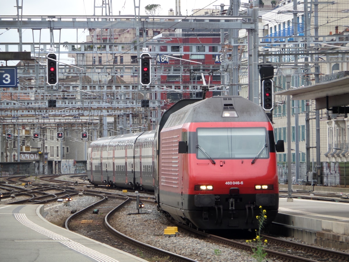 Train de passagers rouge et gris dans une gare urbaine.