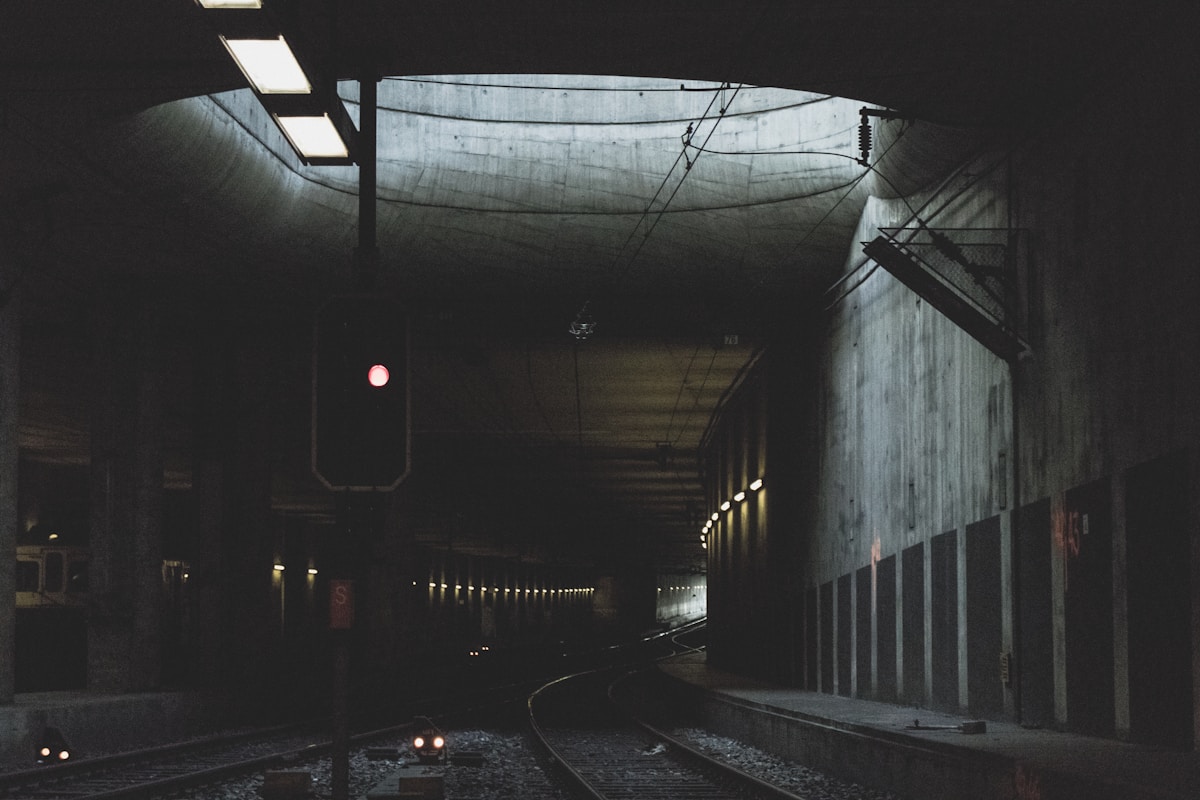 Tunnel sombre et éclairé avec des voies ferrées.