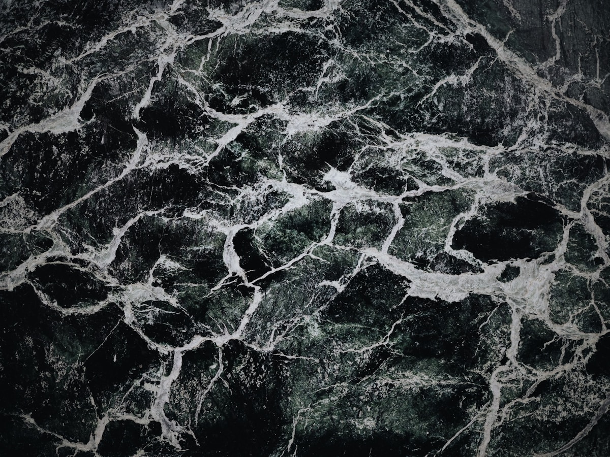 Motif de marbre noir et vert foncé avec des veines blanches.