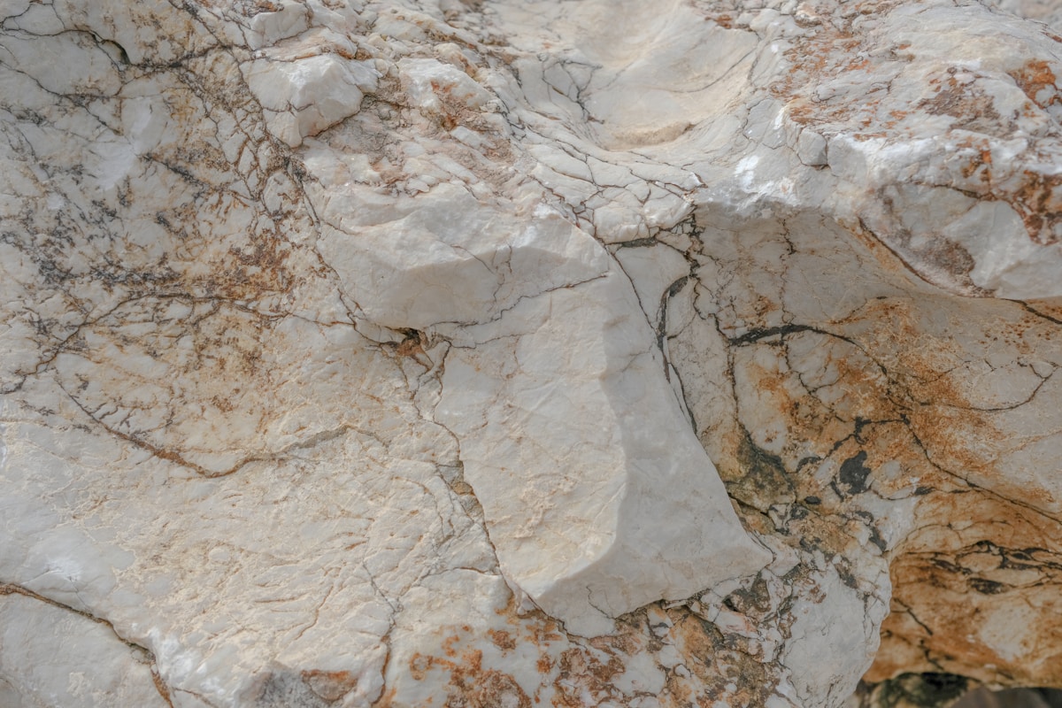 Texture de marbre gris et beige avec des veines et des fissures.