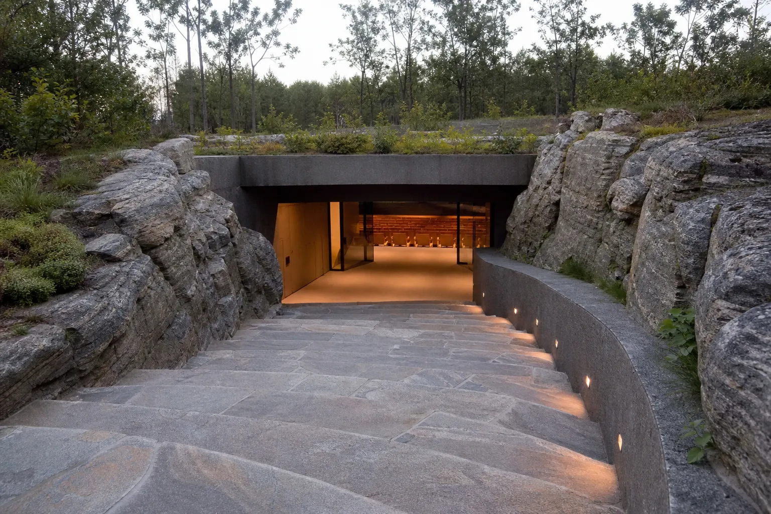 "Chemin en pierre naturelle menant à un auditorium souterrain, illustrant les propriétés acoustiques de la pierre pour l'isol
