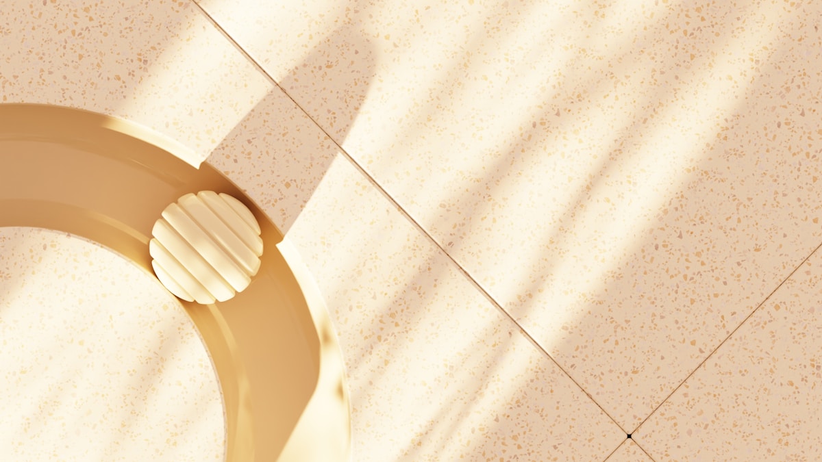 Carrelage beige avec motifs, lampe dorée sur pied.