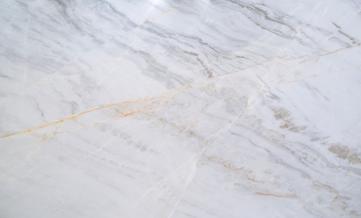 Texture de marbre blanc avec des veines dorées.