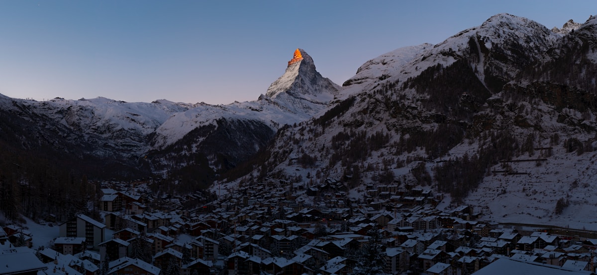 Paysage montagneux enneigé avec le Cervin illuminé au coucher du soleil.