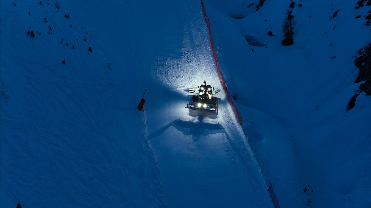 Véhicule tout-terrain sur une piste enneigée dans un paysage montagneux.