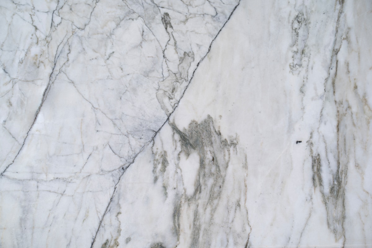 Texture de marbre blanc avec des veines grises et des motifs irréguliers.