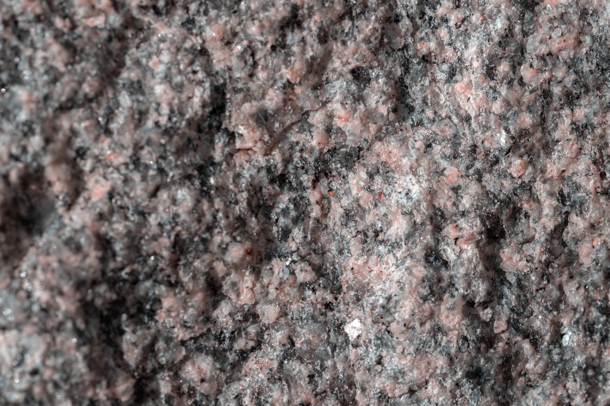 Texture de pierre granitique grise et rose avec des minéraux.