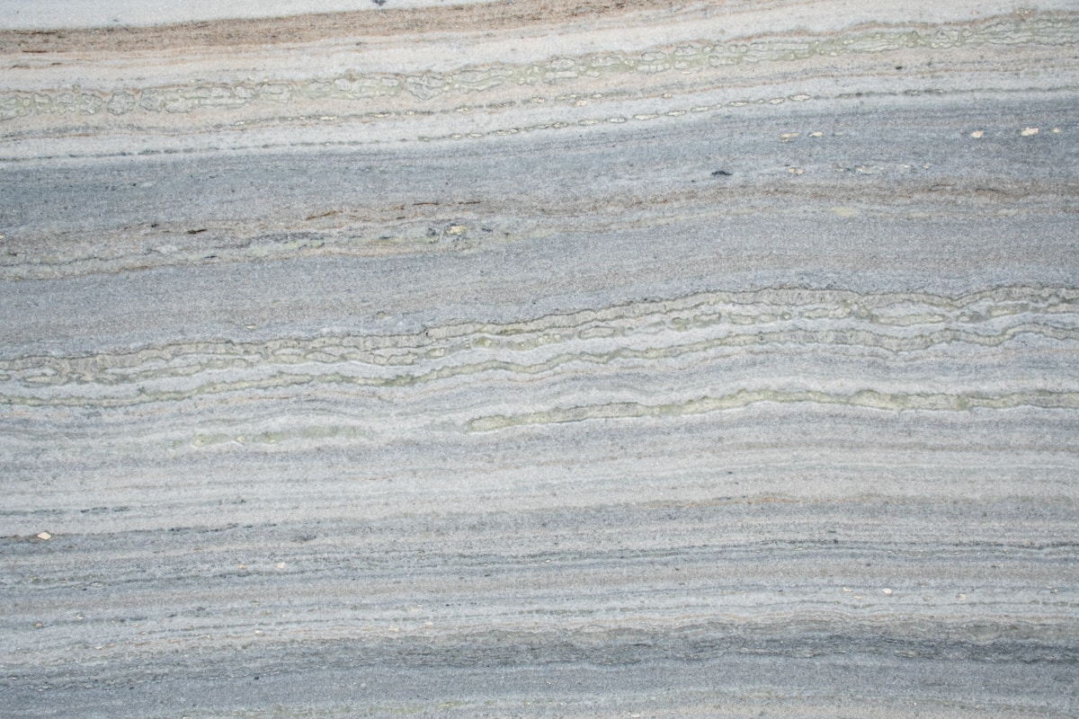 Texture de pierre naturelle aux stries grisâtres et dorées.