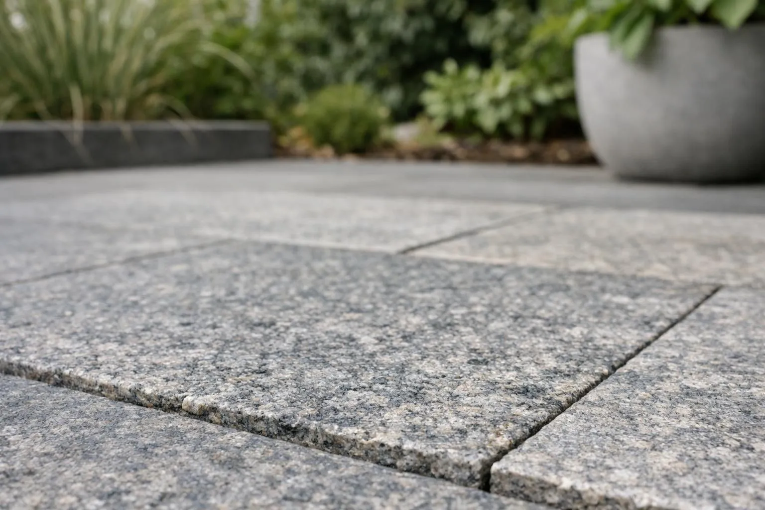 Carrelage en pierre grise texturé dans un jardin verdoyant.