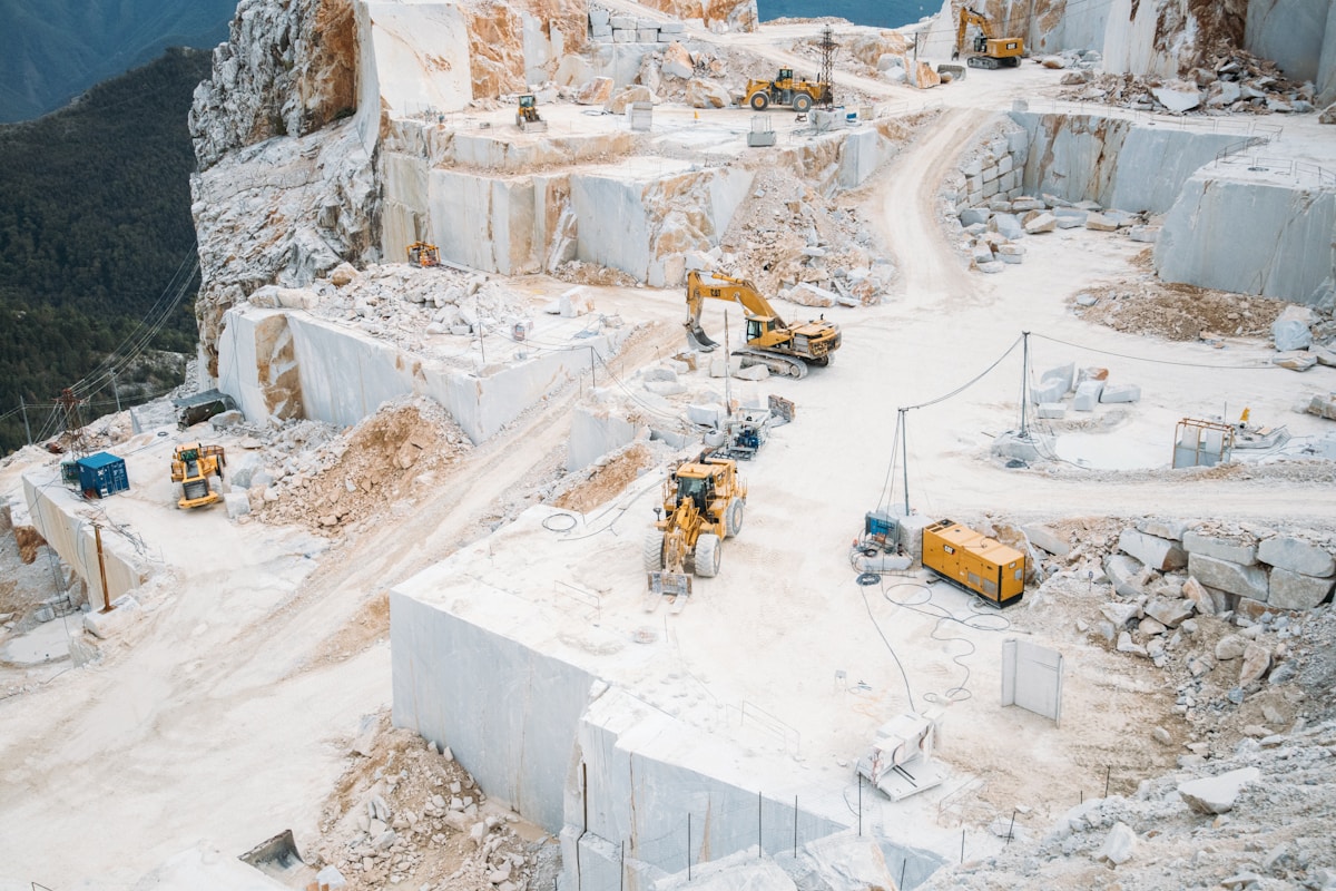 Carrière de marbre avec engins de chantier et excavations profondes.