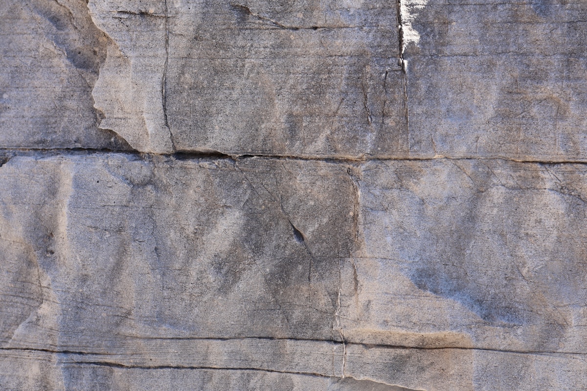 Texture de pierre grise avec fissures et motifs irréguliers.