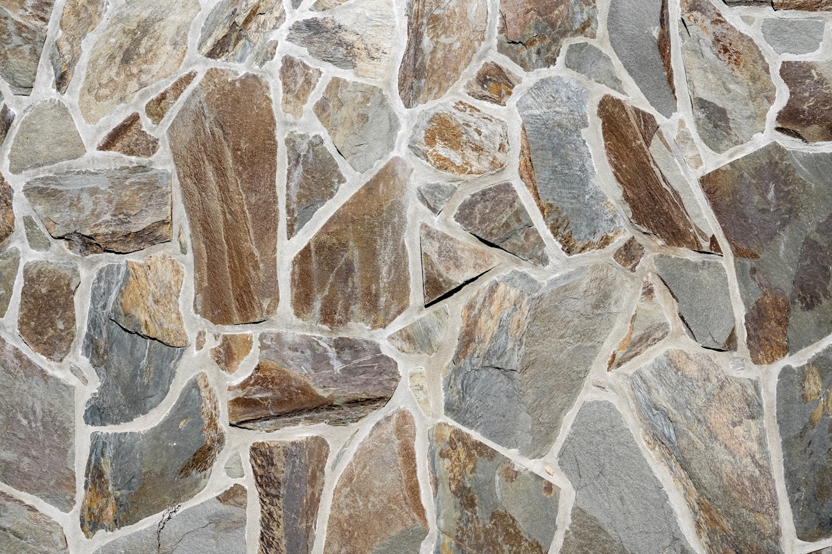 Mur de pierres naturelles de couleurs variées, textures et formes irrégulières.