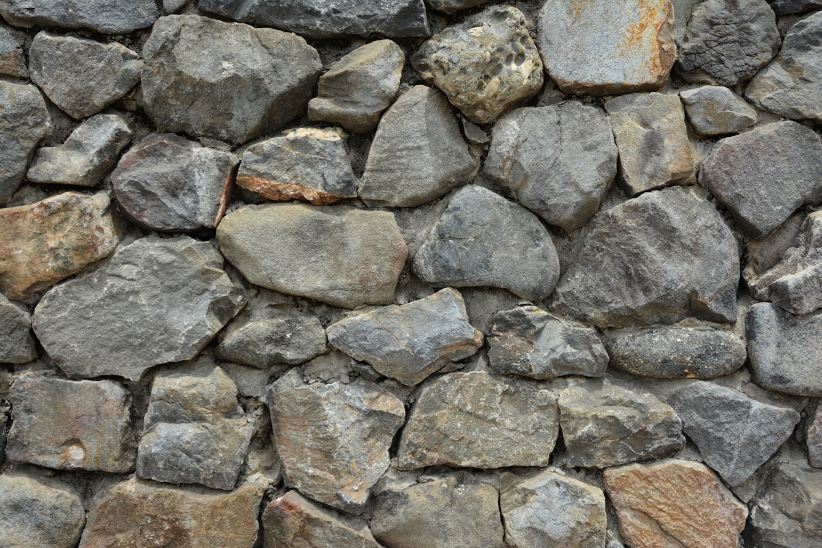 Mur de pierres grises et brunes irrégulières.