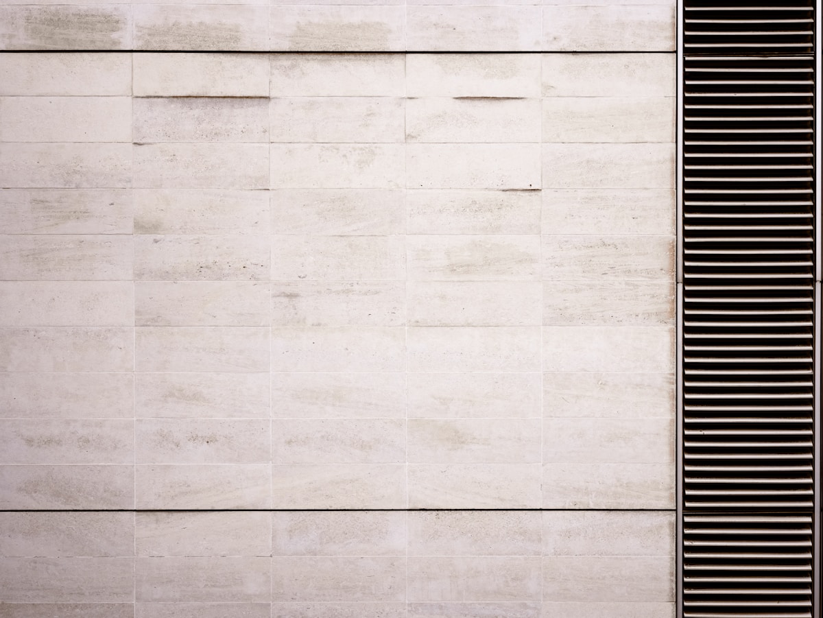 Mur de pierre blanche avec des lignes noires verticales.